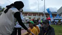 Relawan yang bertugas menjadi Satgas Prokes PON XX membagikan masker kain kepada warga yang ada di dalam kawasan Stadion Lukas Enembe (Dok. BNPB)