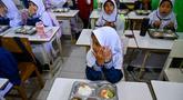 Para siswa berdoa sebelum menyantap makanan yang dipasok oleh program Makan Bergizi Gratis (MBG) di sebuah sekolah dasar, Banda Aceh pada Kamis 30 Oktober 2025. Sejak awal tahun 2025, program Makan Bergizi Gratis (MBG) di Banda Aceh diketahui telah berjalan baik. (CHAIDEER MAHYUDDIN/AFP)