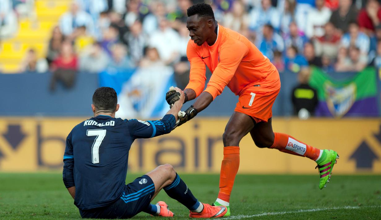 Striker Real Madrid, Cristiano Ronaldo, dibantu kiper Malaga, Carlos Kameni, setelah terjatuh dalam laga La Liga Spanyol di Estadio La Rosaleda, Minggu (21/2/2016) malam WIB. (AFP/Jorge Guerrero)