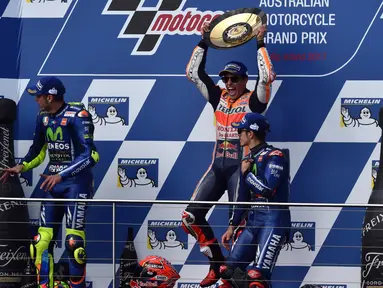 Pembalap Repsol Honda, Marc Marquez (tengah) mengangkat trofi usai keluar sebagai juara MotoGP Australia di Phillip Island (22/10). Dalam MotoGP Australia ini tempat kedua diisi Rossi dan ketiga menjadi milik Vinales. (AFP Photo/Paul Crock)