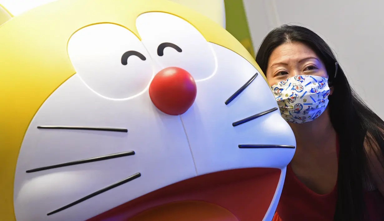 Seorang wanita berfoto dengan patung Doraemon di pameran "Doraemon's Time-Travelling Adventures in Singapore" yang digelar di Museum Nasional Singapura pada 3 November 2020. Pameran ini akan berlangsung hingga 27 Desember 2020. (Xinhua/Then Chih Wey)