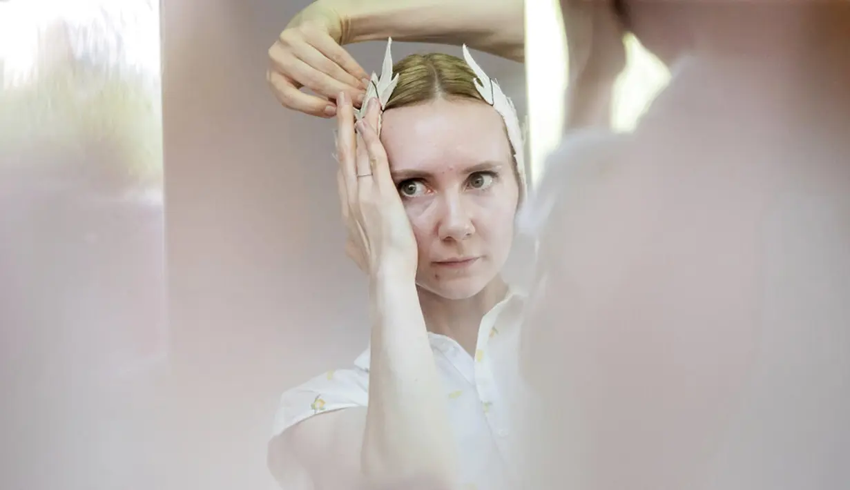 Penari dari Berlin State Ballet meletakkan bulu angsa pada rambutnya saat bercermin di atas kapal pesiar sebelum tur pusat kota di Berlin, Jerman, Kamis (10/6/2021). Pertunjukan itu diikuti oleh banyak orang di sepanjang rute . (Christoph Soeder/dpa via AP)