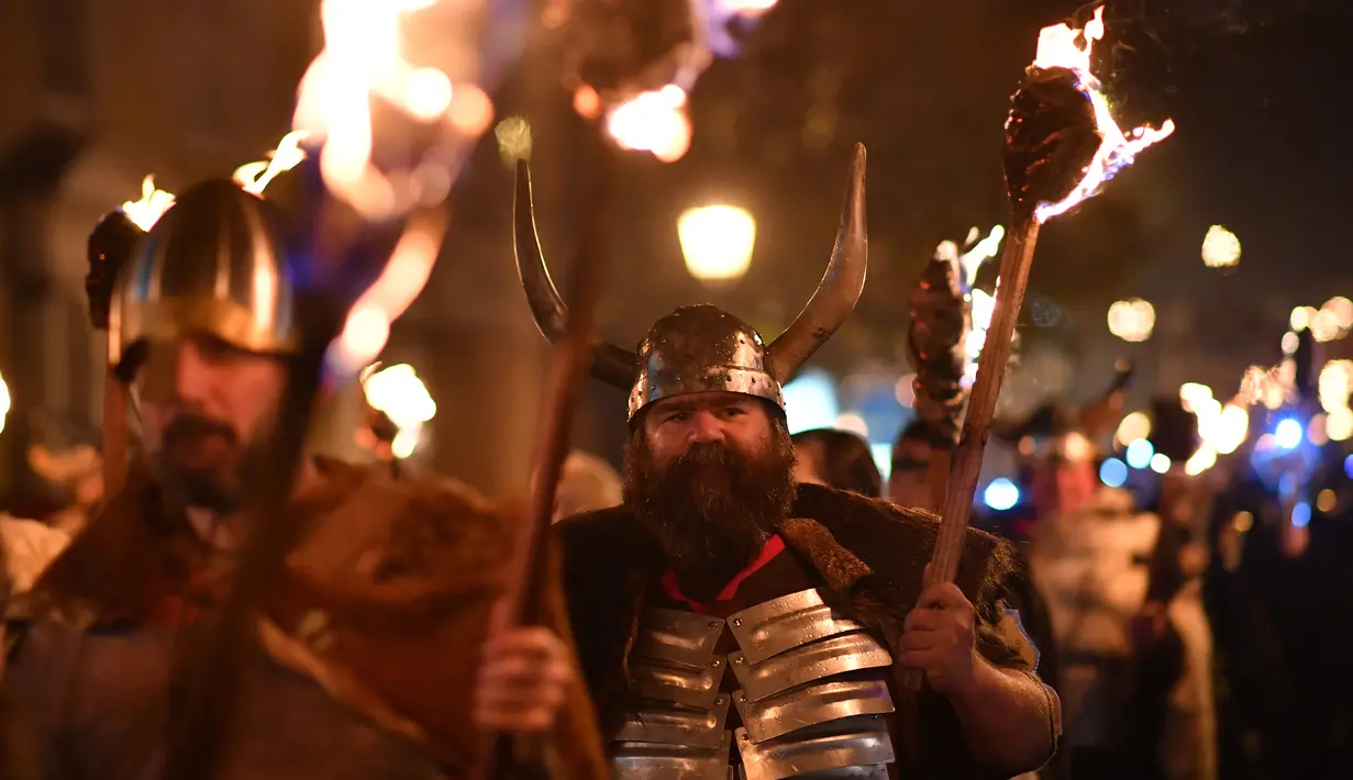 Peserta melakukan pawai sambil membawa obor dalam perayaan Bonfire Night melintasi jalan di Sussex Timur, Inggris, Selasa (5/11/2019). Obor yang mereka bawa itu nantinya akan digunakan untuk menyalakan kembang api dan api unggun. (Ben STANSALL/AFP)