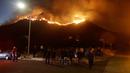 Warga menyaksikan kebakaran hutan dari sudut jalan di West Hills, California, AS, Jumat (9/11). Kebakaran ini dilaporkan telah menewaskan sembilan orang. (AP Photo/Marcio Jose Sanchez)