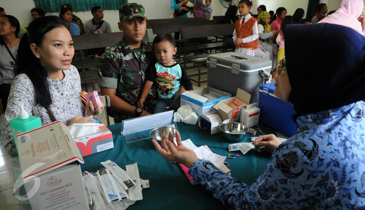 Anggota TNI bersama istri dan anaknya mendaftar vaksinasi ulang di Kantor Kesehatan Kopassus, Jakarta, Senin (18/7). Kopassus menggelar vaksinasi ulang terhadap anak prajurit yang terindikasi menjadi korban vaksin palsu. (Liputan6.com/Helmi Afandi)