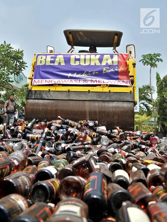 Buldozer melindas ribuan botol minuman keras ilegal saat dimusnahkan di Kantor Bea Cukai Marunda, Jakarta, Selasa (2/10). Total barang bukti rokok dan minuman keras ilegal yang dimusnahkan sekitar Rp 1,1 miliar. (Merdeka.com/Iqbal Nugroho)
