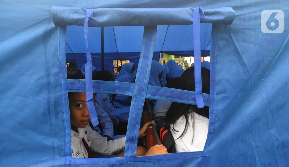 Murid-murid berada di dalam tenda darurat  akibat bangunan atau kelas roboh saat hujan deras  pada hari Rabu (1/1/2020) lalu di SDN Cirimekar 2, Cibinong, Bogor, Senin (6/1/2020). (merdeka.com/Arie Basuki)