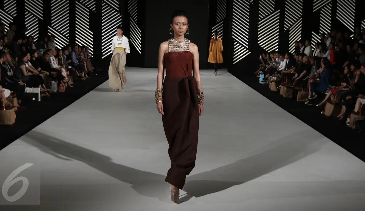 Model membawakan busana rancangan teranyar Andreas Odang pada malam pembukaan Senayan City Fashion Nation ke-11, Kamis (6/4). Sebanyak 15 busana wanita hadir dalam balutan warna-warna hangat, gelap, dan cenderung muted. (Liputan6.com/Herman Zakharia)