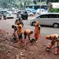 Petugas PPSU atau yang lebih dikenal dengan sebutan Pasukan Oranye membersihkan sendimen tanah merah yang longsor ke jalan Galunggung, Jakarta, Selasa (30/8/2016). (Liputan6.com/Yoppy Renato)