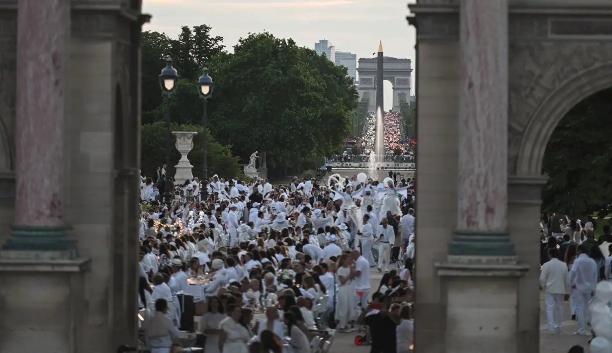 Para peserta dalam balutan serba putih  berkumpul untuk Dinner en Blanc atau "makan malam putih" di Tuileries Gardens, Paris, Kamis (6/6/2019). Mereka berkumpul untuk menggelar makan malam terbuka, yang berlangsung di tempat berbeda di Paris setiap tahun. (Lucas BARIOULET/AFP)