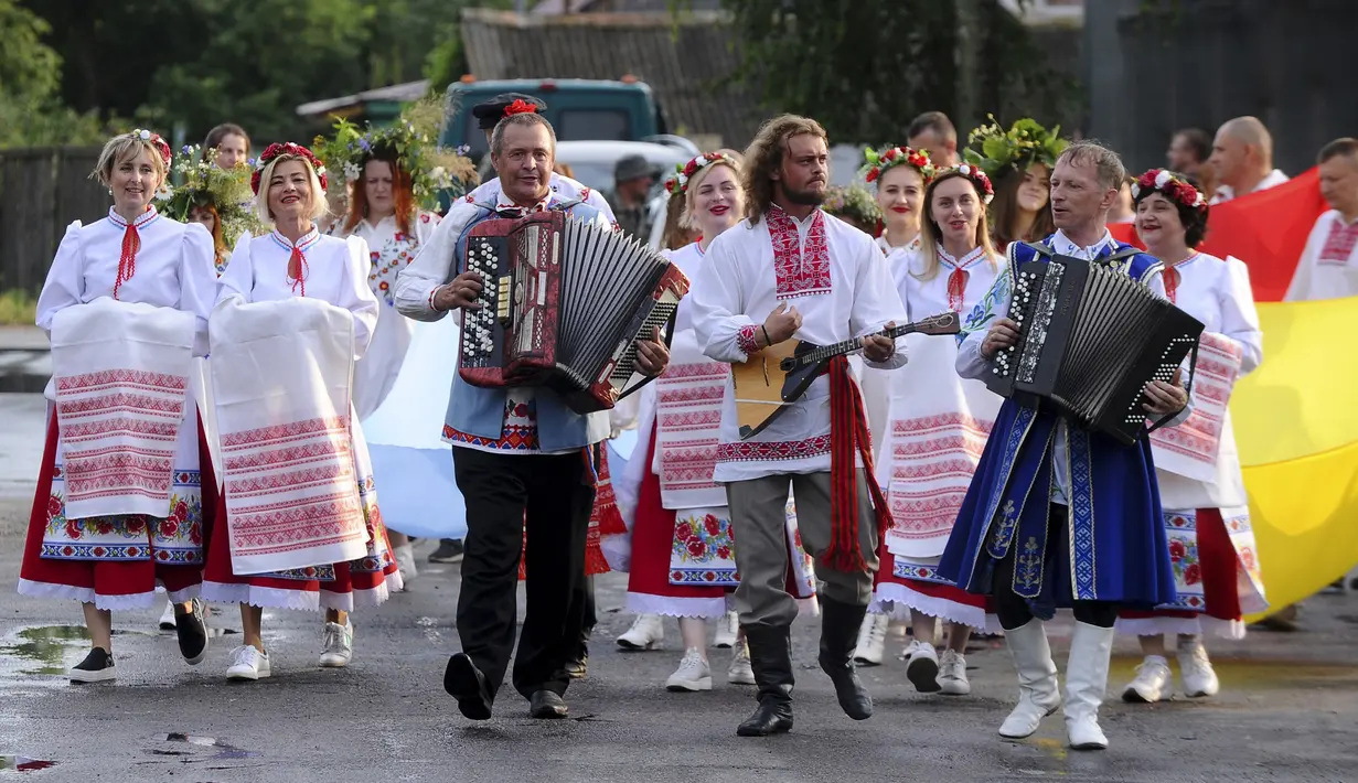 Warga Belarusia dengan kostum nasional berjalan ke Sungai Berezina pada Hari Ivan Kupala di Desa Parichi, sekitar 200 km (125 mil) selatan Minsk, Belarusia, 6 Juli 2022. Ivan Kupala atau Hari St. John atau Hari Pertengahan Musim Panas adalah karnaval tradisional yang berpusat di sekitar api unggun dengan banyak makanan dan tarian. (AP Photo/Viktor Drachev)