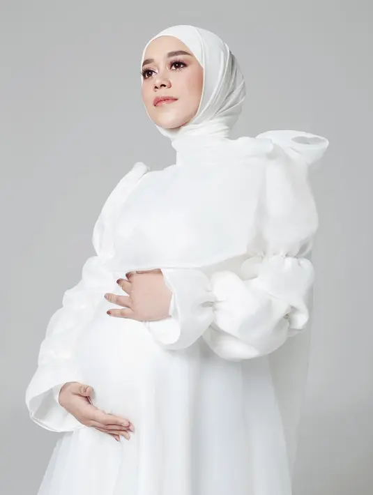 Warna putih memang tidak pernah salah. Seperti terlihat dalam maternity shoot Lesty Kejora ini, ia mengenakan dress dengan lengan panjang berkerut. Dress putih polos ini dipermanis dengan detail pita di bagian bahu. Foto: Instagram.