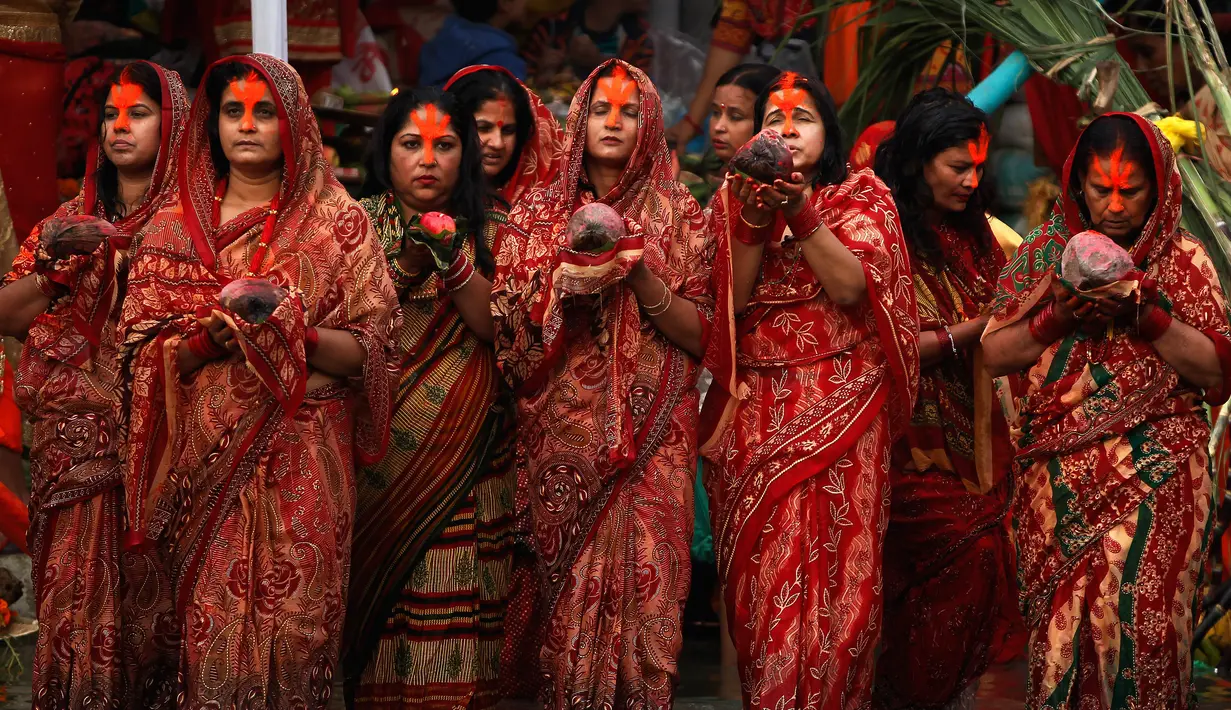 Sejumlah wanita Nepal berdoa saat matahari terbenam selama festival Chhath Puja di tepi Sungai Bagmati, Kathmandu, Nepal (26/10). (AP Photo/Niranjan Shrestha)