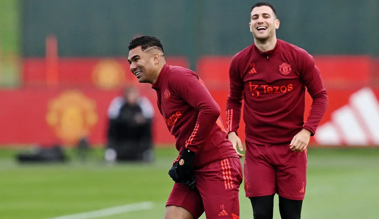 Pemain Manchester United, Casemiro dan Diogo Dalot, tampak semringah saat sesi latihan di Carrington Training Complex, Senin (23/10/2023). Mereka tampak bercanda dan tertawa bersama di sesi latihan. (AFP/Paul Ellis)
