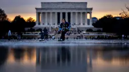 Lincoln Memorial terlihat saat Jacek Zavora (21) dari Arlington bermain hoki di Reflecting Pool yang membeku, National Mall, Washington, Amerika Serikat, 26 Desember 2022. Banyak warga memposting pengalaman tersebut ke media sosial. (AP Photo/Andrew Harnik)