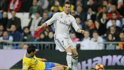 Bintang Real Madrid, Cristiano Ronaldo (kanan) berusaha melewati hadangan pemain Las Palmas, Vicente Gomez pada lanjutan La Liga Spanyol di Santiago Bernabeu stadium, Madrid, (1/3/2017). Madrid bermain imbang 3-3. (AP/Paul White)