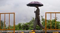 Seorang wanita memegang payung dan berjalan saat hujan di Kohima, Nagaland, India, Senin (16/5/2022). Delapan orang tewas akibat banjir dan tanah longsor yang dipicu oleh hujan lebat di wilayah timur laut India. (AP Photo/Yirmiyan Arthur)