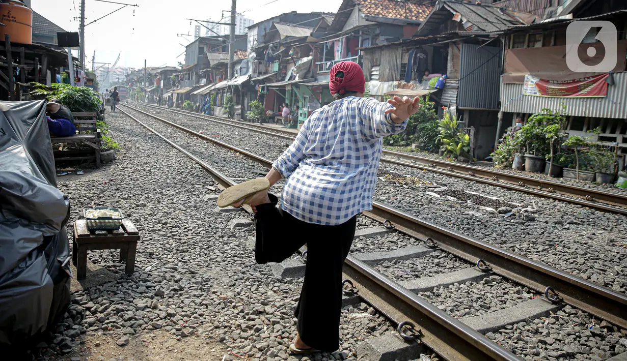 Warga berolah raga ringan sambil berjemur di bantaran rel di kawasan pemukiman padat Pejompongan, Jakarta, Selasa (6/7/2021). Berjemur diri di bawah matahari di antara pukul 08.00-11.00 WIB merupakan salah satu upaya menjaga kesehatan selama wabah virus COVID-19. (Liputan6.com/Faizal Fanani)