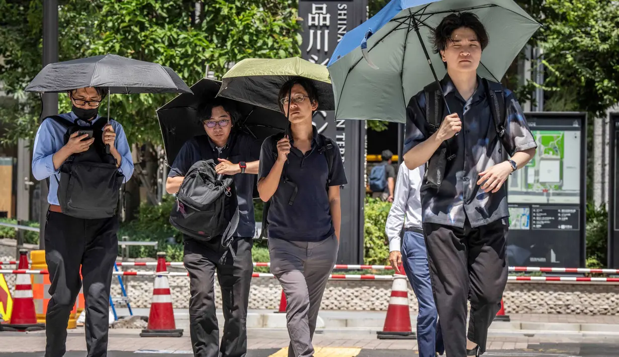 Orang-orang melindungi diri dari terik matahari dengan payung di Tokyo pada 27 Agustus 2025. (Yuichi YAMAZAKI/AFP)