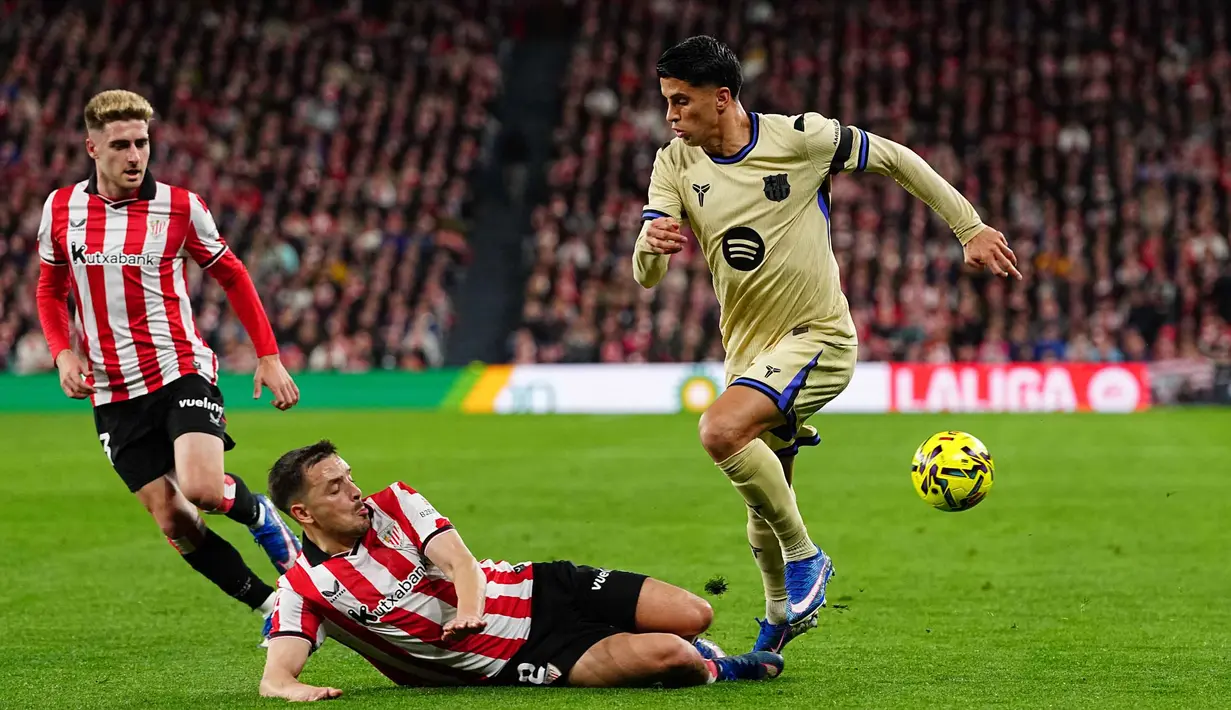 Meski dominan dalam penguasaan bola, Barcelona kesulitan menembus pertahanan Athletic Bilbao yang bermain dengan disiplin sejak awal laga. Skor imbang 0-0 bertahan hingga akhir babak pertama. Tampak dalam foto, pemain Athletic Bilbao, Andoni Gorosabel (tengah), mencoba mengadang Joao Cancelo dari Barcelona (kanan) pada pertandingan pekan ke-27 La Liga 2025/2026 di Stadion San Mames, Sabtu 7 Maret 2026 waktu setempat atau Minggu (8/3/2026) dini hari WIB. (AP Photo/Miguel Oses)