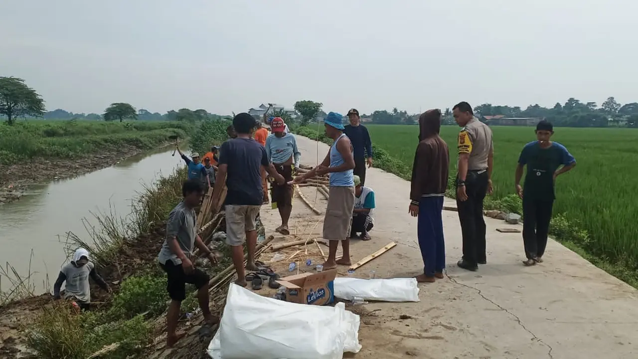 Warga bersama polisi memperbaiki tanggul yang jebol pasca diterjang banjir. (Liputan6.com/Bam Sinulingga)