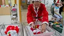 Dokter mengenakan busana santa claus memeriksa bayi-bayi yang baru lahir di Paolo memorial hospital di Bangkok, Thailand (21/12). (AP Photo / Gemunu Amarasinghe)