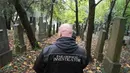 Aksi seorang pemburu hantu menelusuri batu nisan untuk mencari aktivitas gaib di pusat pemakaman tua di Wina, Austria, 20 Oktober 2016. Pemakaman ini disinyalir memiliki aura mistis yang kental dengan aktivitas makhluk halus. (JOE KLAMAR/AFP)