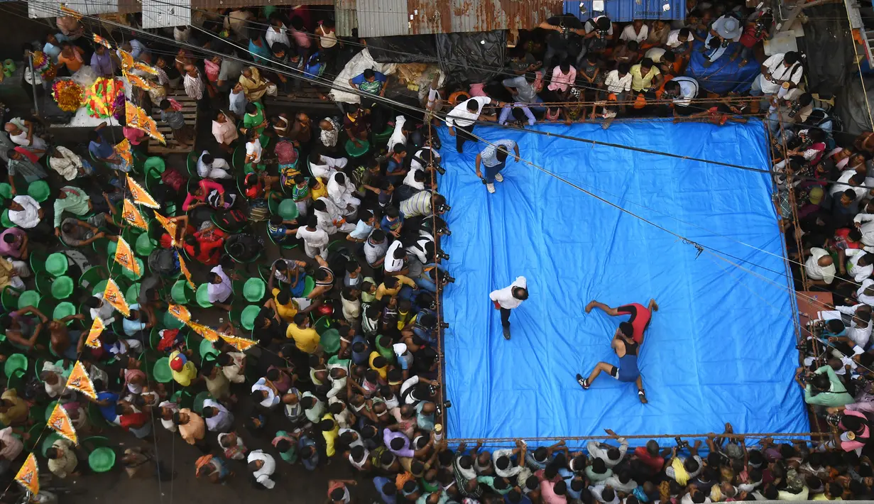 Pegulat amatir India bertarung saat mengikuti kompetisi untuk menyambut perayaan Diwali di Kolkata, India (18/10). Pertandingan gulat ini digelar di tengah jalan yang padat di daerah Kolkata. (AFP Photo/Dibyangshu Sarkar)