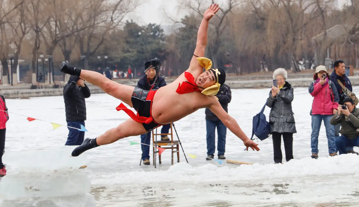 Seorang perenang musim dingin yang mengenakan kostum melompat ke dalam danau yang sebagian membeku di Shenyang, provinsi Liaoning, China, Selasa (19/2). Mereka percaya berendam di sungai dengan suhu yang ekstrem baik untuk kesehatan. (Photo by STR / AFP)