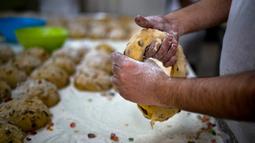 Seorang tukang roti membentuk adonan untuk membuat Bolo Rei atau Kue Raja di toko roti Padaria da Ne, Amadora, Portugal, 16 Desember 2022. Untuk tahun ini, pemenang Bolo Rei terbaik di Portugal adalah sebuah toko roti kecil di Damaia, Amadora. (CARLOS COSTA/AFP)