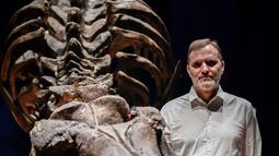 Ahli paleontologi, Ronan Allain berpose di depan kerangka dinosaurus Tyrannosaurus Rex di Museum Nasional Sejarah Alam Prancis di Paris, 1 Juni 2018. Setelah disusun, Trix memiliki tinggi sekitar 4 meter dan panjang 12,5 meter. (AFP/STEPHANE DE SAKUTIN)