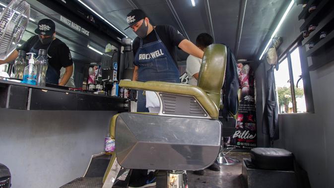 Seorang tukang cukur terlihat di dalam mobil van atau truck yang diubah menjadi barbershop di sebuah jalan di tengah pandemi virus corona COVID-19, di Mexico City, pada Minggu (6/9/2020). (Photo by CLAUDIO CRUZ / AFP)