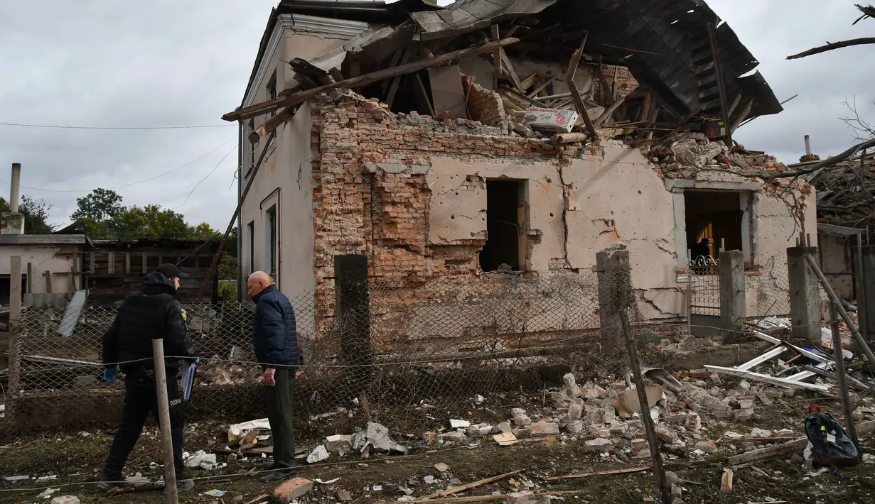 Serangan ini disebut sebagai yang terbesar di wilayah barat Lviv sejak invasi dimulai pada 2022. Disebut-sebut, serangan tersebut melibatkan 140 drone dan 23 rudal yang diluncurkan dari berbagai arah. Tampak dalam foto, seorang petugas penyelamat bersama warga sipil memeriksa puing-puing rumah yang hancur akibat serangan roket Rusia di pinggiran Lviv, Ukraina, Minggu 5 Oktober 2025. (AP Photo/Mykola Tys)