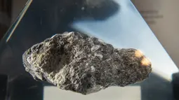 Batu dari Bulan terpajang dalam wadah kaca akrilik jelang perayaan 50 tahun misi Apollo di atas kapal USS Hornet, Alameda, California, Amerika Serikat, Selasa (16/7/2019). Tidak ada yang diizinkan untuk menyentuh batu tersebut secara langsung. (JOSH EDELSON/AFP)