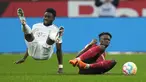 Penyerang Bayern Munchen, Alphonso Davies dan bek  Bayer Leverkusen Jeremie Frimpong terjatuh saat bertabrakan pada laga pekan ke-25 Liga Jerman 2022/2023 di Stadion BayArena, Senin (20/3/2023) dini hari WIB. (AP Photo/Martin Meissner)