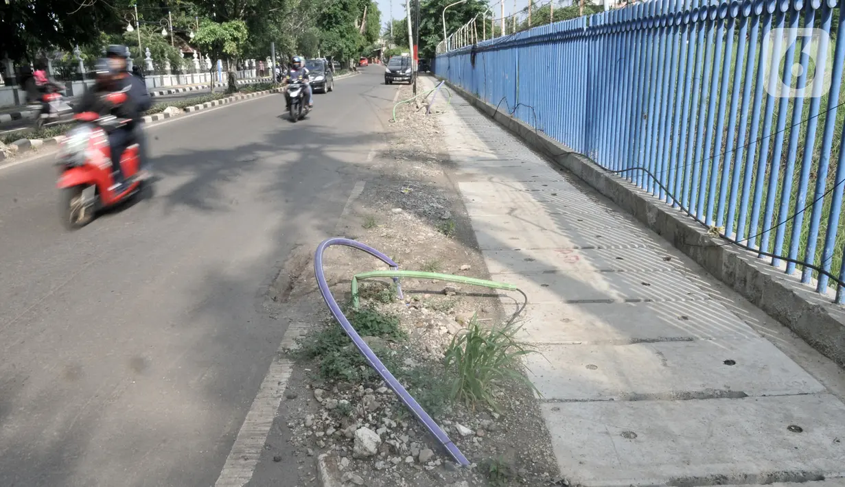 Kendaraan melintasi kabel proyek PLN yang terbengkalai di Jalan Jatinegara Kaum, Jakarta, Minggu (12/1/2020). Kurangnya pengawasan dalam penyelesaian proyek instalasi listrik bawah tanah PLN tersebut menyebabkan banyak kabel masih muncul di trotoar dan bahu jalan. (merdeka.com/Iqbal S. Nugroho)