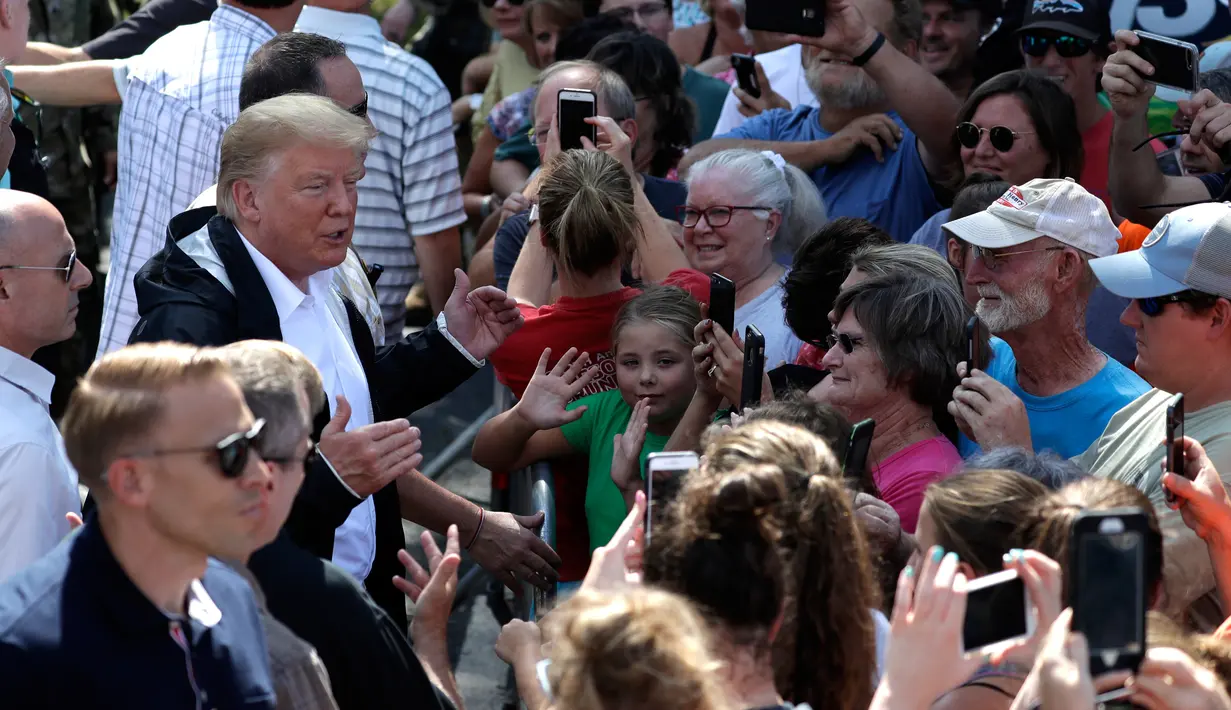 Presiden AS, Donald Trump berbincang dengan korban badai Florence di Temple Baptist Church di New Bern, N.C. (19/9). Badai tersebut juga membuat hampir seluruh kota di North Carolina dibanjiri lumpur dan air. (AP Photo /Evan Vucci)