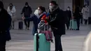Para pemudik yang memakai masker mendorong kopernya menuju pintu masuk Stasiun Kereta Api Beijing di Beijing, China, Sabtu (14/1/2023). Jutaan warga China diperkirakan akan melakukan perjalanan selama periode liburan Tahun Baru Imlek tahun ini. (AP Photo/Mark Schiefelbein)