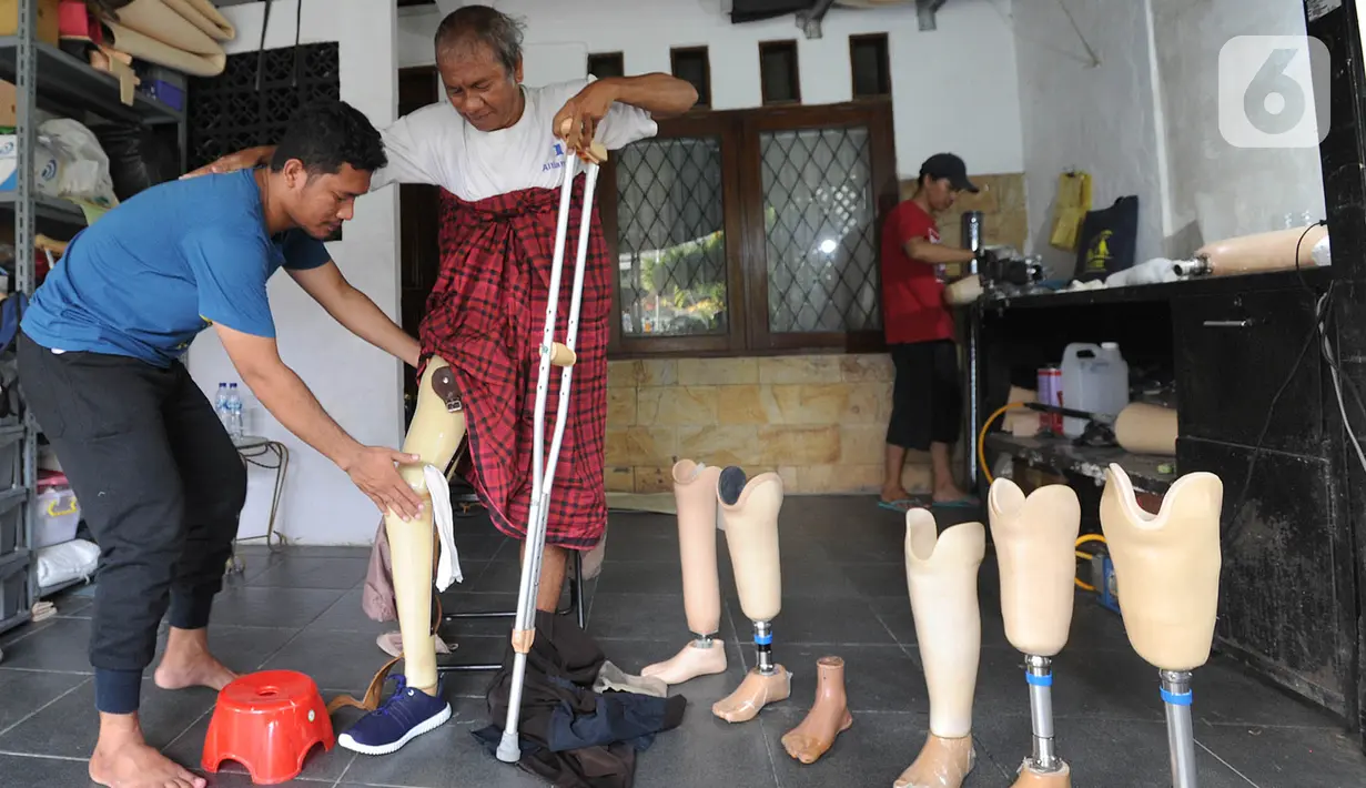 Ortotis prostetis atau pembuat kaki tangan palsu memasangkan kaki palsu buatannya kepada penyandang disabilitas di sebuah bengkel kawasan Ciputat Baru, Tangerang Selatan, Banten, Senin (14/10/2019). Kaki dan tangan palsu dijual dengan harga Rp 5 juta hingga Rp 50 juta. (merdeka.com/Arie Basuki)