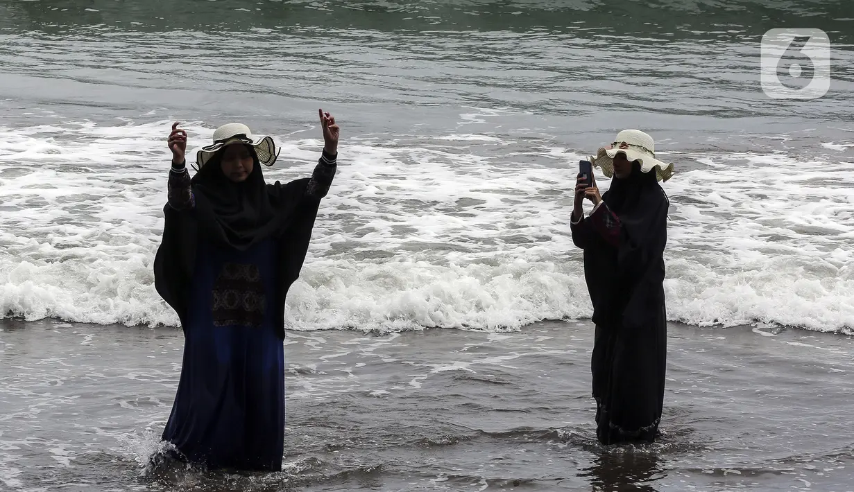 Warga berswafoto di Pantai Pelabuhan Ratu, Kabupaten Sukabumi, Jawa Barat, Jumat (12/11/2021). Pantai Pelabuhan Ratu menjadi tempat wisata favorit warga Jawa Barat serta Jakarta dan sekitarnya. (Liputan6.com/Johan Tallo)