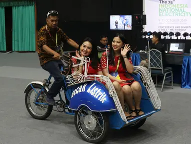 Dua wanita menaiki becak listrik selama pameran pada Hari Listrik Nasional di JCC, Jakarta, Rabu (9/10/2019). HLN ke-74 mengusung tema "Keberlanjutan Sektor Ketenagalistrikan dalam Menghadapi Era industri 4.0". (Liputan6.com/Angga Yuniar)