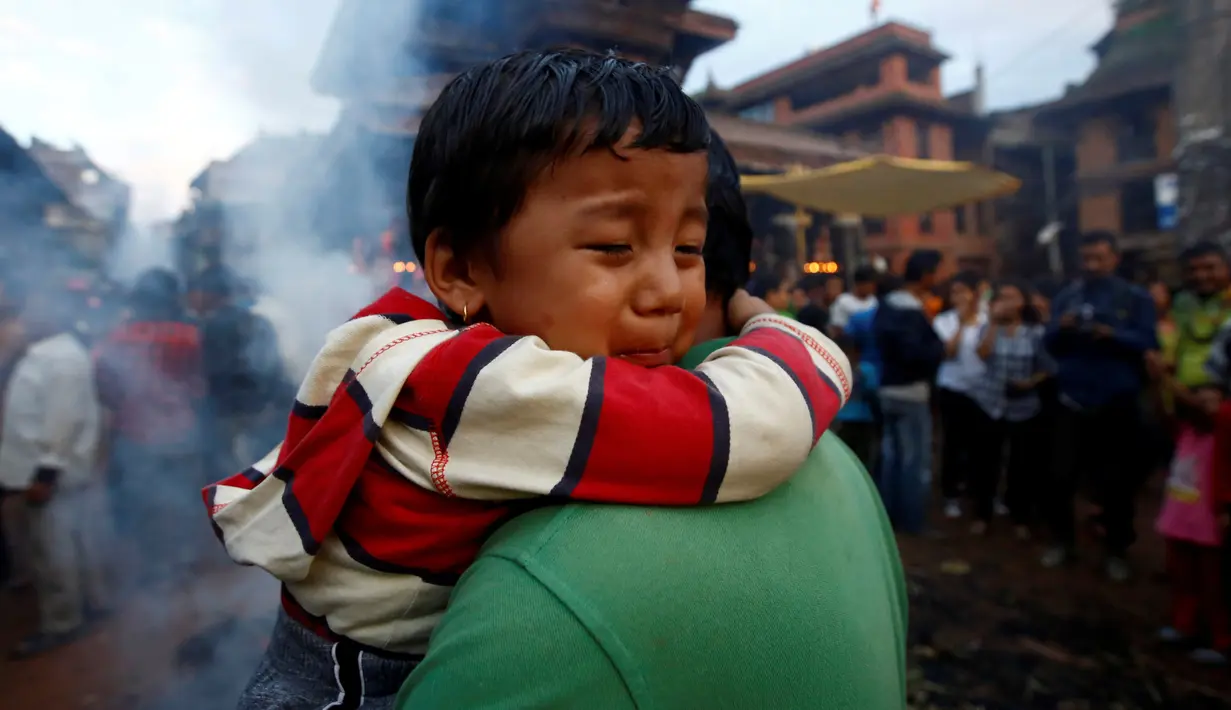Seorang anak menangis saat ikut menyaksikan pembakaran boneka dari jerami yang dianggap sebagai setan Ghantakarna selama Festival Ghantakarna di kota kuno Bhaktapur, Nepal, Senin (1/8). (REUTERS/Navesh Chitrakar)