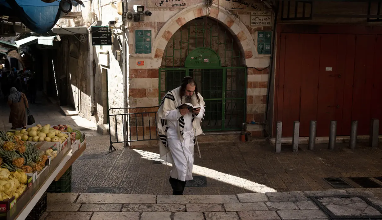 Seorang umat Yahudi membaca buku doa tentang Yom Kippur, Hari Pendamaian Yahudi, saat ia berjalan di Kota Tua Yerusalem, Senin (25/9/2023). (AP Photo/Maya Alleruzzo)