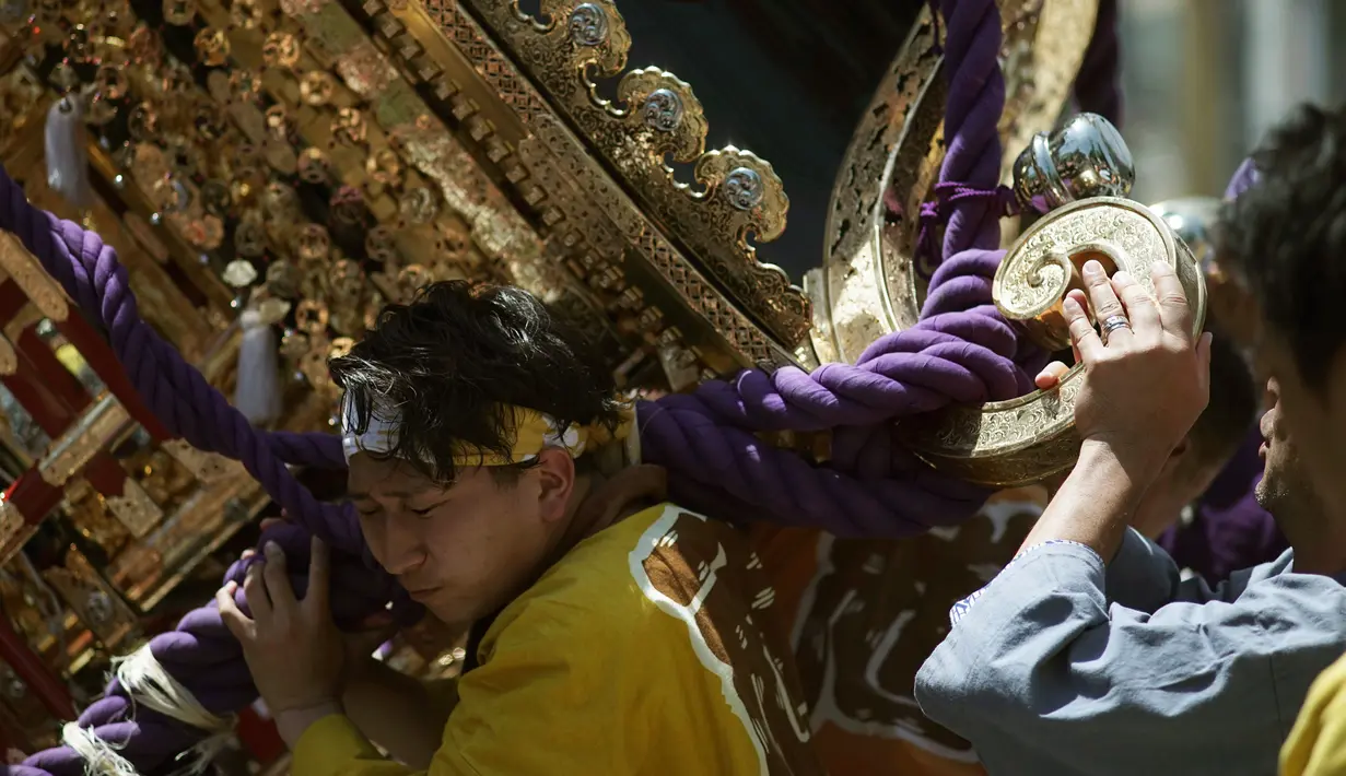 Ekspresi peserta saat mengayunkan Mikoshi atau tempat suci portabel selama festival Tenno-sai di Kuil Susanoo di Tokyo, Jepang (3/6). Festival Tenno-sai ini diyakini dapat mengusir penyakit menular di musim panas. (AP Photo / Eugene Hoshiko)