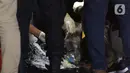 Petugas Basarnas bersama tim DVI Polri mengecek barang temuan yang diduga serpihan pesawat Sriwijaya Air SJ 182 di Dermaga JICT 2, Jakarta, Minggu (10/1/2021) dini hari. Sriwijaya Air SJ 182 hilang kontak dalam penerbangan dari Jakarta menuju Pontianak. (Liputan6.com/Helmi Fithriansyah)