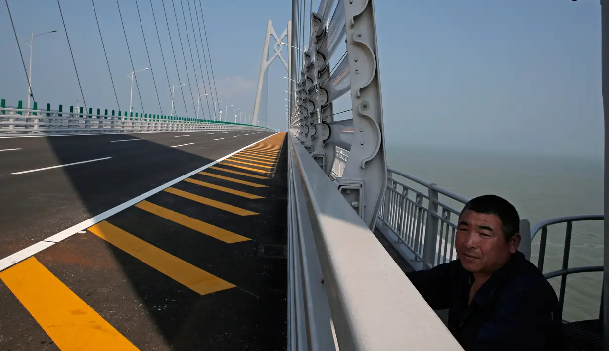 Seorang pekerja berdiri di Jembatan Hong Kong-Zhuhai-Macau di kota Zhuhai, China selatan, Rabu (28/3). Jembatan laut terpanjang di dunia tersebut menunggu pemeriksaan kualitas akhir sebelum dapat dibuka secara resmi. (AP Photo/Kin Cheung)