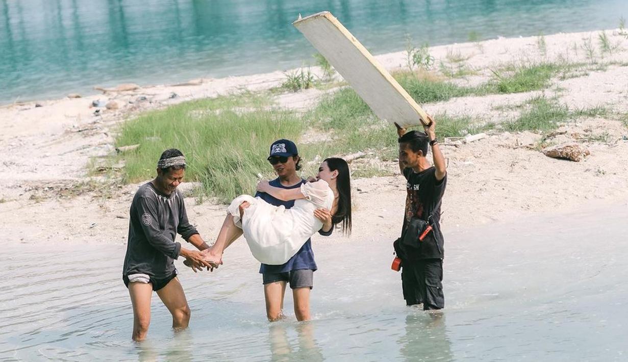 Berlokasi di sebuah pulau kecil, akses menuju tempat syuting pun cukup menantang. Alhasil, Shandy Aulia harus digendong oleh salah satu kru agar gaun yang dikenakannya tidak basah kuyup. Dalam komentar, banyak warganet merasa iri dengan kru sinetron yang beruntung menggendong sang aktris. (Liputan6.com/IG/@shandyaulia)