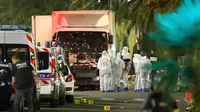 Polisi dan ahli forensik berdiri disamping sebuah truk yang menabrak kerumunan orang yang tengah menyaksikan festival di Nice, Prancis, Kamis (14/7). Sedikitnya 60 orang tewas dan ratusan lainnya luka akibat hantaman truk tersebut. (REUTERS/Eric Gaillard)
