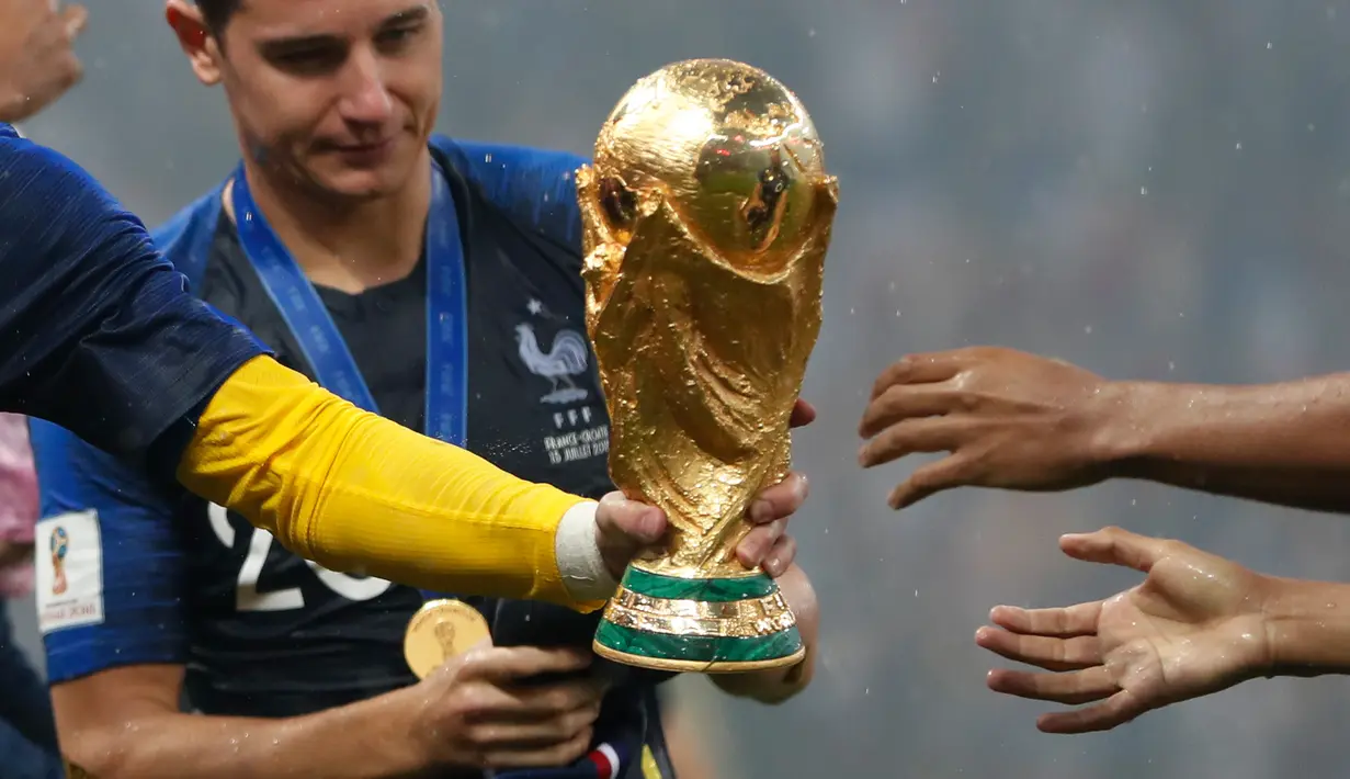 Kiper timnas Prancis, Hugo Lloris memberikan trofi Piala Dunia 2018 kepada rekan setimnya pada perayaan gelar juara pada  laga final di Luzhniki Stadium, Minggu (15/7). Prancis membekuk Kroasia dengan skor akhir 4-2. (AP Photo/Natacha Pisarenko)