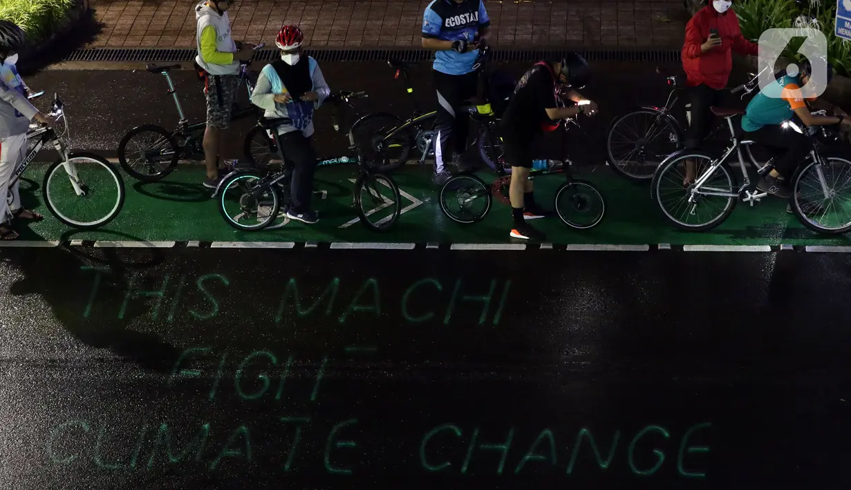 Pegiat bersepeda dan aktivis pecinta lingkungan saat aksi gowes Kelap Kelip Jakarta Night Ride #NOP26 di Kawasan Dukuh Atas, Jalan Jenderal Sudirman, Jakarta, Jumat (26/11/2021). Aksi bertujuan untuk mendorong penggunaan sepeda sebagai solusi transportasi nol emisi. (Liputan6.com/Helmi Fithriansyah)